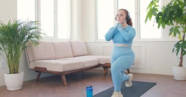 Mavi spor giyimli çekici kızıl saçlı kız fitness, yavaş çekim aktif yaşam tarzı, sağlıklı yoga hobisi üzerine yoğunlaşmış.