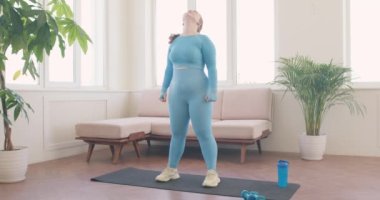 Güzel obez kızıl saçlı kadın egzersiz yapıyor, evde ısınıyor, gözleri kapalı kız başını öne, arkaya, sağa, sola eğiyor, kadın sabah egzersizi yapıyor, yavaş çekim sağlığını koruyor.