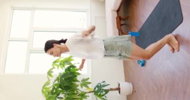 Evde ip atlayıp zıplayan çekici, zayıf ve aktif bir kızın portresi sağlıklı kardiyo aktivitelerine yoğunlaşmıştı. dikey video yavaş çekim yaşam tarzı boş zaman hobisi