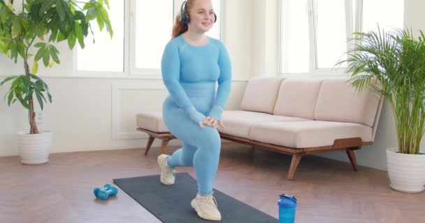 Fat Happy Uśmiechnięta Kobieta Słuchawkach Robi Przysiady Lunges Ćwiczenia Stojąc — Wideo stockowe