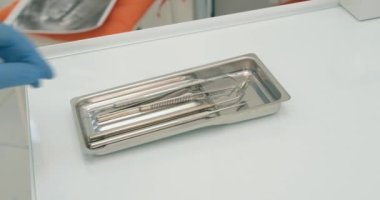 Dişilerin elleri masadan stomatoloji aletini alıyor. Dişçi ameliyata hazır olsun. Diş sağlığı konsepti.