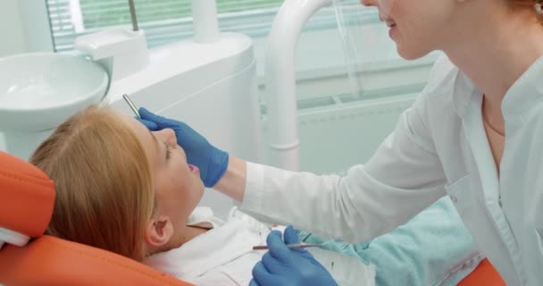 Rothaarige Ärztin Diagnostiziert Behandelt Zahnfleischprobleme Zähne Kleines Blondes Mädchen Mit — Stockvideo