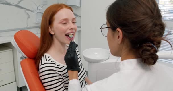 Talentosa Doctora Sondeando Dientes Mujer Pelirroja Con Instrumento Dental Usando — Vídeo de stock
