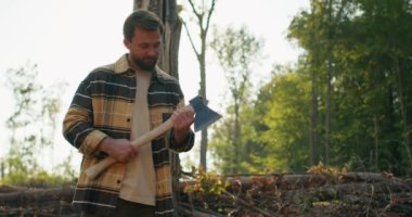 Yakışıklı, mutlu, güler yüzlü, sakallı oduncu ormanda dinleniyor, kameraya bakıyor, elinde baltayla dönüyor, omuzunda yemek aleti, beleş boş zaman liestyle yavaş çekim