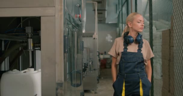 懒惰的金发女工 身穿特殊制服 手插在口袋里休息在杀虫剂生产厂慢动作关闭罐体制造工艺 — 图库视频影像