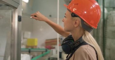 Koruyucu elbiseli genç sarışın kadın, tornavida kullanarak cam kutuyu açıyor, tamir ediyor, tamir ediyor, yan görünümü kapatıyor ağır çekimde feminizm portresi çiziyor.