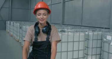 Mutlu gülümseyen fabrika işçisi depoda içi böcek ilacı dolu ağır bir konteynırı şeffaf bir kamyonla taşıyor. Feminizm meslek mesleği ağır çekim