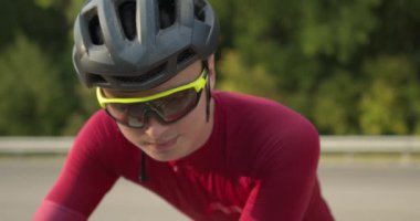 Yorgun, düşünceli, mutsuz, kasklı ve güneş gözlüklü üzgün sporcu bisikletle otururken aşağıya bakıyor. Yavaş çekim portre hatası kaybedildi