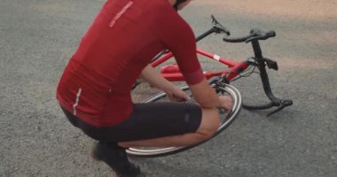 Kasklı ve spor giyimli bir sporcu bisiklet pompası kullanıyor, adamın bisikletle sorunu var. Bisikleti kendi kuvvetleriyle tamir etmek, detayları değiştirmek, hareket sorunu, bisiklet tamiri. yavaş çekim