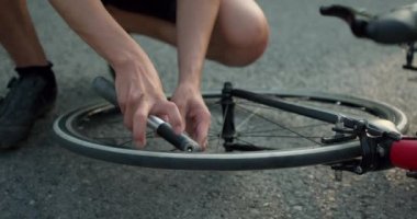 Genç MNA 'lar bisikletten bitap düşmüş, sporcu bisiklete dokunuyor, mahsulü yavaş çekim videosu çekiyor. Bisiklet tüpünü, tekerleği tamir ediyorum. Tüpü pompayla şişirir..