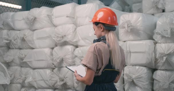 ヘルメットの女の子と工場でパック化学プラスチック容器を数える特別な制服 手にクリップボードのフォルダを保持し 準備農薬を販売する準備ができています 職場の女性が — ストック動画