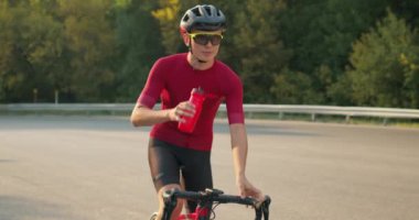 Şişeden su içen susuz, terli bir bisikletçi. Triatloncu triatlon sporunda izotonik içecek kullanır. MTB Bisiklet Eğitiminden Sonra Bisikletçi Hidrasyonu. Sporcu Dinleniyor