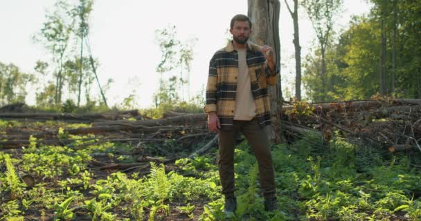 伐採シーズンだ 森林伐採で一日働いた後 肩に斧を持つ白人ハンサムな疲れLumbermanは休息しています 木を切る 夏の自然 自然の風景 生態環境 — ストック動画