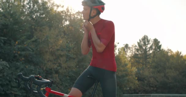 若いハンサムな男は サイクリングトライアスロン競技の準備 自転車用ヘルメットを着用するサイクリスト 集中的な心臓サイクリングトレーニングの練習の前にプロのアスリート 自転車に乗るサイクリストアスリート — ストック動画