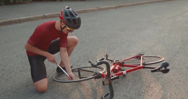 헬멧을 자전거 타이어를 다니는 스포츠맨 선수는 밖에서 펌프로 자전거 바퀴를 — 비디오