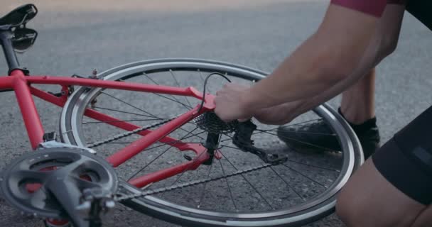 自転車で問題を解決しようとする若いスポーツマンは車輪を修理し — ストック動画
