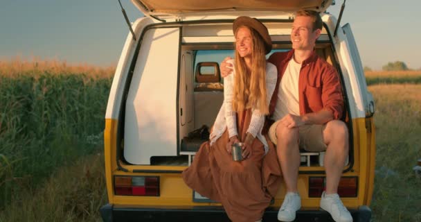 美しい風景を指し 自然の美しさを楽しむ 一緒にコーンフィールドで日没の時計 カジュアルに身を包んだ 日没を見てヴァンで座って若い幸せな興奮素敵なカップル アドベンチャータイム — ストック動画