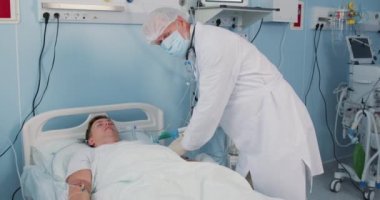 Profesyonel deneyimli yaşlı doktor ve hemşire iğneyi tutarken konuşuyor, modern hastanede röntgen çektirirken, genç bir adama nasıl davranılması gerektiğini tartışırken, tıbbi tedavi konseptini incelerken. yavaş çekim