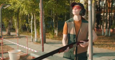 Genç bir kadın hedefe nişan alıyor, yukarı bakıyor, kız parkta atış yapmayı öğreniyor yaz güneşli bir günde güvenlik ve güvenlik sporu oyunu Yavaş çekim Skeet Sport.