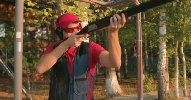 カジュアルなTシャツ キャップ 保護眼鏡ヘッドセットを身に着けている若い男は鳥を殺す ハンターは銃で練習しています射撃範囲で銃で自己防衛技術を向上させるために射撃 — ストック動画