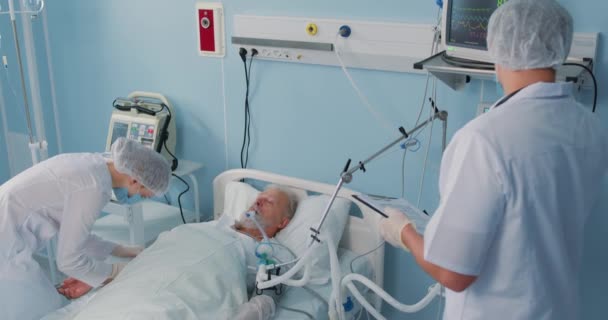 リハビリテーションの専門知識 スローモーションを分析しながら 病人の老人患者はベッドで休んでいます 病院での緊急事態 医師は心拍数を確認する手を握っています 医者が老人を見舞いに — ストック動画