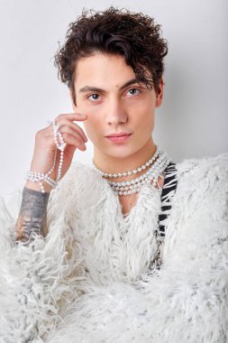 Beyaz stüdyo arka planında izole edilmiş beyaz kabarık kürklü, efemine görünümlü, kendine güvenen beyaz erkek portresi. gençlik, güzellik, moda, tarz, parti, lgbt, transseksüel konsept