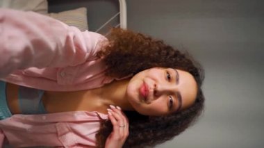 Oldukça genç kız vlogger uzun dalgalı kıvırcık saçlı akıllı telefonlu kamera görüntüleme video bloğuna konuşan sanal mobil görüntülü sohbet uygulaması dikey video görüntüsü