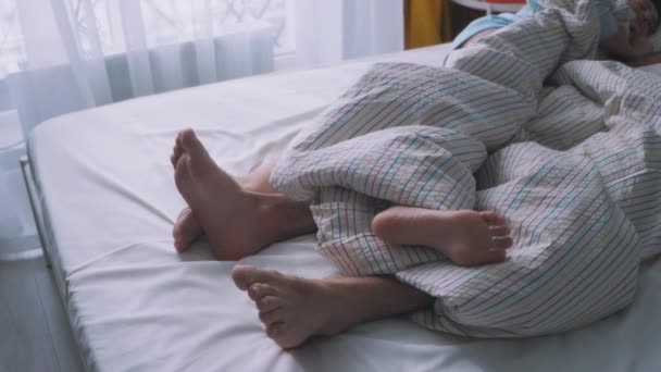 家族のカップルベッドの上で愛 男の足を一緒にベッドルームで抱擁 ロマンチックな恋人の親密な 幸せな家族の中での性的活動 裸の足がブランケットの下にある — ストック動画