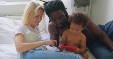 Çeşitli karışık ırk ailelerinin kızlarına videolar göstermesi, online eğitim eğlencesi akıllı telefon öğrenme harfleri, alfabe, cep telefonu kullanan Z jenerasyonu çocukları, video oyunu oynayan ağır çekimli çocuklar.