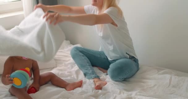 父母可爱的小女孩玩捉迷藏 在卧室里找毛巾 迷人的成年人和好奇的孩子在家里消磨时光 — 图库视频影像