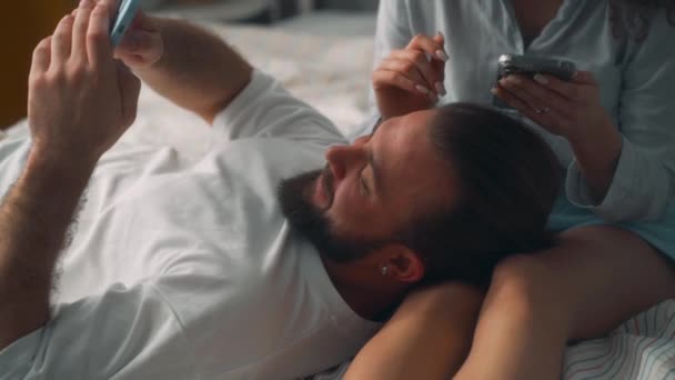 Lächelnd Fröhliches Paar Das Sich Bett Mit Smartphones Hotel Ausruht — Stockvideo