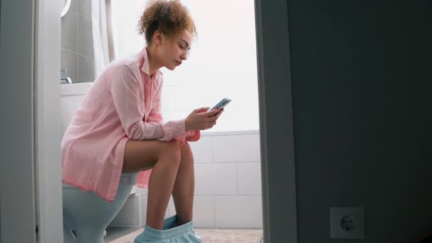 Jovem Mulher Usando Seu Telefone Celular Enquanto Sentada Banheiro Mensagem — Vídeo de Stock