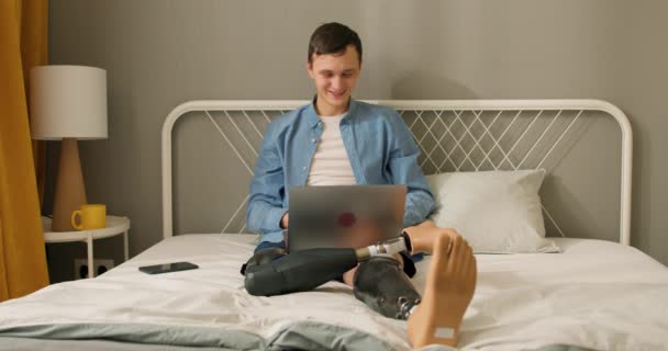 快乐的自由职业者有着人造仿生腿假肢的高加索人在家里的笔记本电脑上远程工作 快乐的人使用笔记本电脑 商人在网上工作 — 图库视频影像