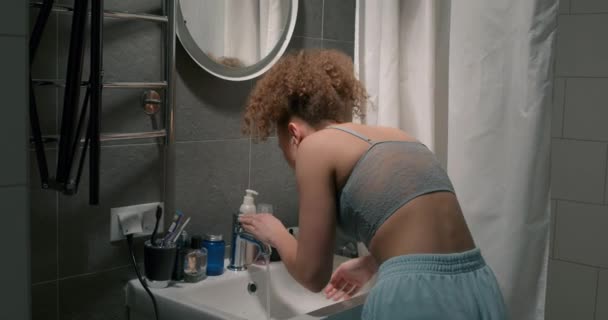 年轻女人刷牙后会刷牙 后视镜 早上穿短裤和蓝色上衣的女孩在浴室里狼吞虎咽 — 图库视频影像
