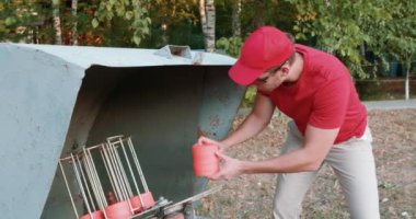 Genç adam kil hedefler koyuyor, Clay disklerini atış için hazırlıyor, açık alanda atış yapmaya hazır. Hobi, adam Clay güvercinlerini ya da av tüfeği disklerini toplar.