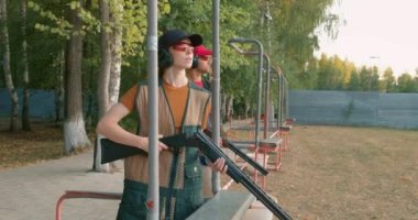 Ciddi adam ve kadın izlemeye odaklanmış, uçan kil diskler, skeetler, ağır çekimler, yarışmaya katılan çiftler,.