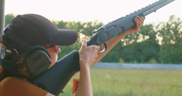 若い男は銃にカートリッジを入れて それをコックし ぐらつき の範囲で狙い 発射する 女性は小さな標的に注目してる 女の子は散弾銃の撃ち方を学ぶ鳥狩りの上達 — ストック動画