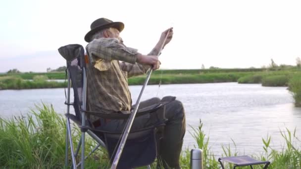 老英俊的大胡子男人戴着帽子 穿着格子衬衫解开连杆 爷爷有连杆 慢动作的问题 上了年纪的高加索人钓鱼 钓到鱼了巴特尔大师去钓鱼了暑假 — 图库视频影像