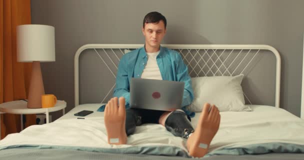 障害のある青白い週の男は ノートパソコン スマートフォン テレビを見て コントロールパネルでテレビをオンにして 自由な時間を過ごす コントローラー余暇の自由時間ライフスタイルの利益 — ストック動画