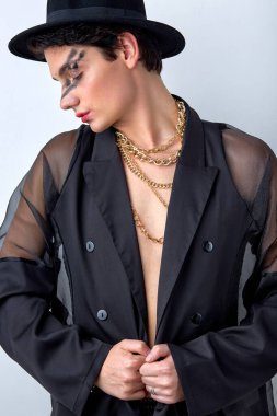 Siyah elbiseli sevimli, muhteşem beyaz eşcinsel yüzü parlak parti makyajıyla aşağıya bakıyor. Beyaz arka planda izole edilmiş güzel, sakin erkek model. portre