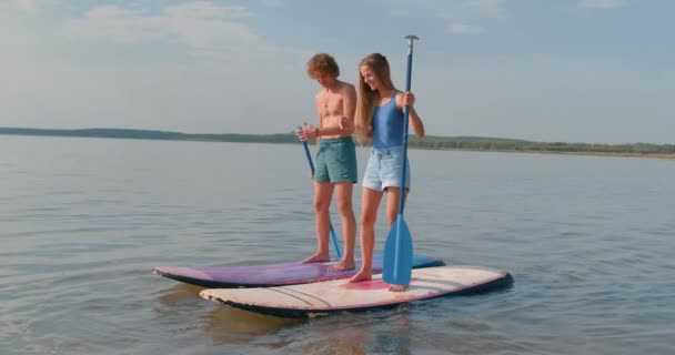 사랑하는 부부는 호수에서 파도타기를 하면서 즐거운 시간을 보내고 연습하고 여름휴가 — 비디오