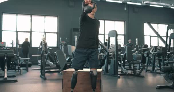 積極的な野心的な障害者の男性はジムでケトルベルを持ち上げます スローモーションライフスタイル無料の時間の健康とボディケアリハビリテーション — ストック動画