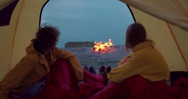 Aile çadırın içindeki dağda dinleniyor. Arka planda şenlik ateşi, akşam, sabah. Kamp, seyahat eden turistler, şenlik ateşinin yanında dinleniyorlar. Gece kampı kavramı, ilişki..