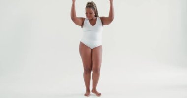 Beyaz mayo giyen seksi, pozitif Afrikalı kadın dans stüdyosunda eğleniyor. Ağır çekim eğlence. Mükemmel tombul, seksi, pürüzsüz tenli vücut.