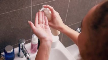 Çekici bir kadın kremi alır, avuç içine, ele sürer, boyuna krem sürer, banyo aynasına bakar, sağIıklı genç bir bayan üzerine nemlendirici krem sürer, cilt bakımı yapar.