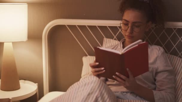 松懈的年轻漂亮聪明的女人在家里躺在床上 戴着眼镜看书 Hobby 亚洲学生正准备参加家庭生活方式的考试 Hobby — 图库视频影像