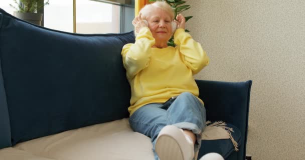 Ηλικιωμένη Συναισθηματική Γυναίκα Κάθεται Άνετα Στον Καναπέ Ακούγοντας Τις Αγαπημένες — Αρχείο Βίντεο
