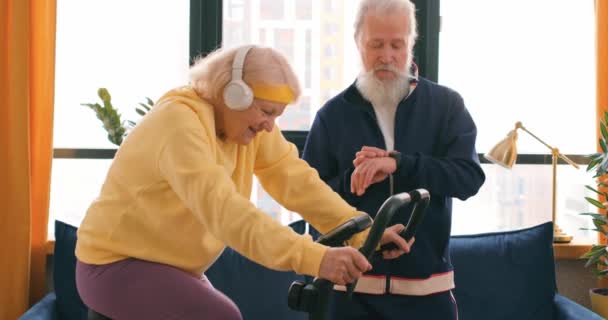 Συνταξιούχος Ενεργό Κυρία Κατάρτισης Σταθερό Ποδήλατο Στο Σπίτι Προσωπικό Γυμναστή — Αρχείο Βίντεο