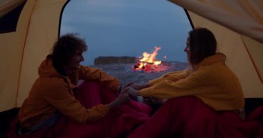 Aile dışarıda harika vakit geçiriyor, sevgi dolu bir çift el ele tutuşuyor. Erkek ve kadın çadırın içinde oturuyor, beyaz bir çift aşık, doğada, spor giysiler içinde.