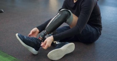 Yapay bacaklı genç sporcu spor salonunda ayakkabısını bağlıyor ağır çekimde spor ayakkabı bağlayan adam spor ayakkabı bağlayan adam spor ayakkabısı bağlayan adam, motivasyon için hazırlanıyor boş zaman.